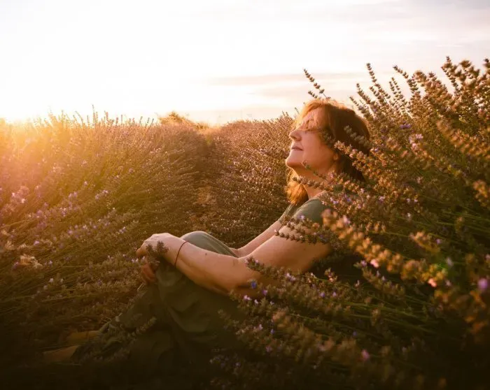 Mujer sentada en un campo de lavanda al atardecer